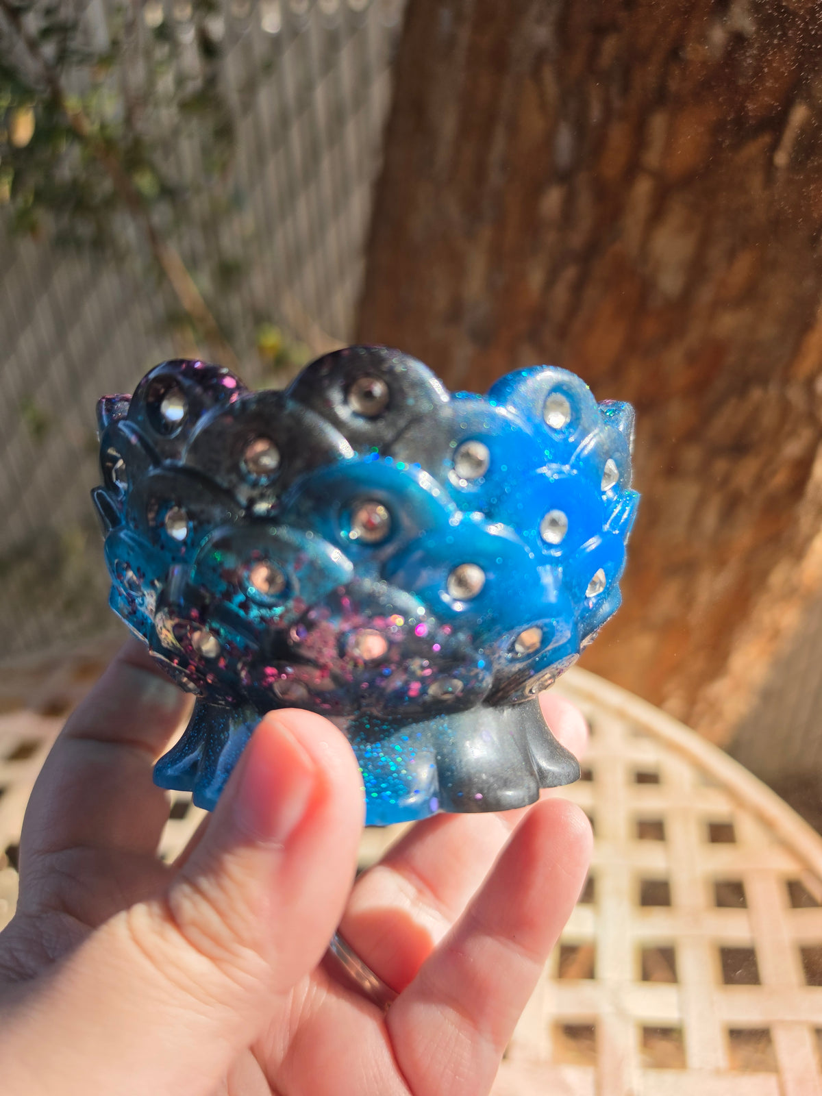 Cobalt blue and navy galaxy resin scalloped bowl with embedded rhinestones held in hand outdoors