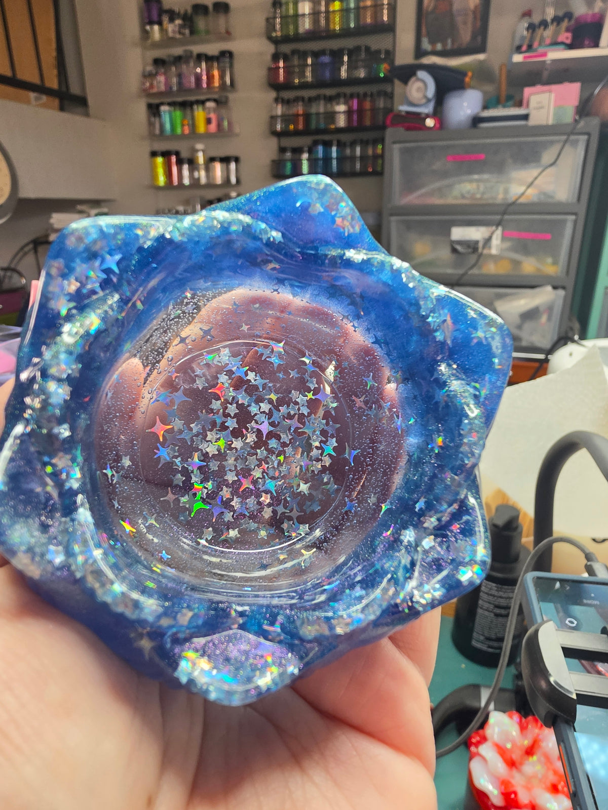 Hand holding cobalt blue galaxy lotus resin dice throne showing star confetti and holographic glitter detail in bowl