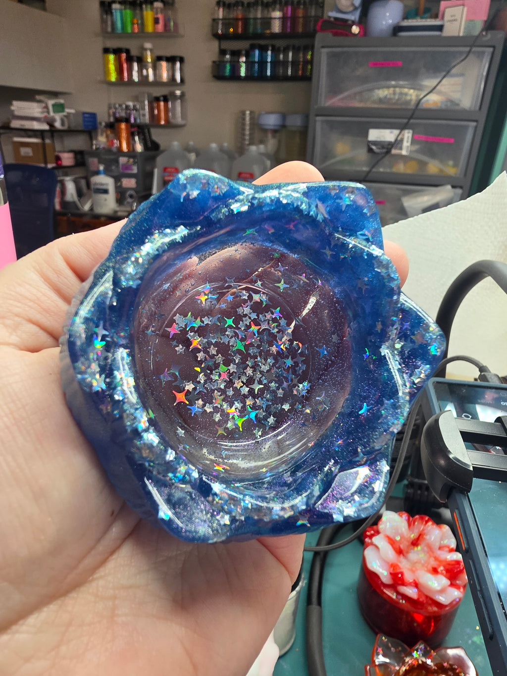 Top-down view of midnight blue lotus dice throne showing holographic star confetti scattered across bowl interior