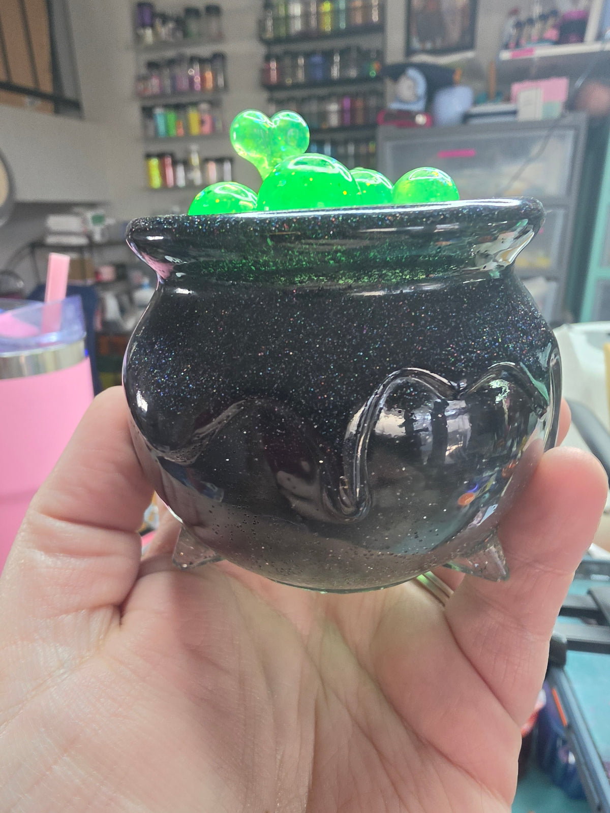 Full cauldron view showing classic three-footed silhouette with handle details and green bubble lid