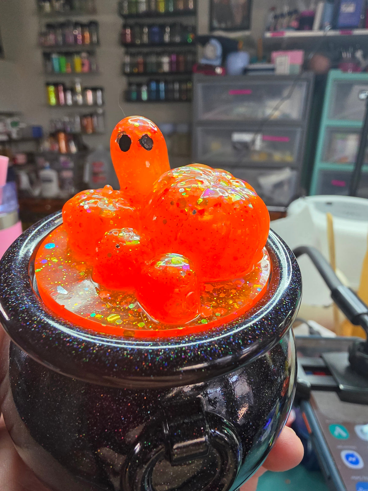 Close-up of orange glitter resin pumpkin lid with ghost figure and holographic glitter chunks
