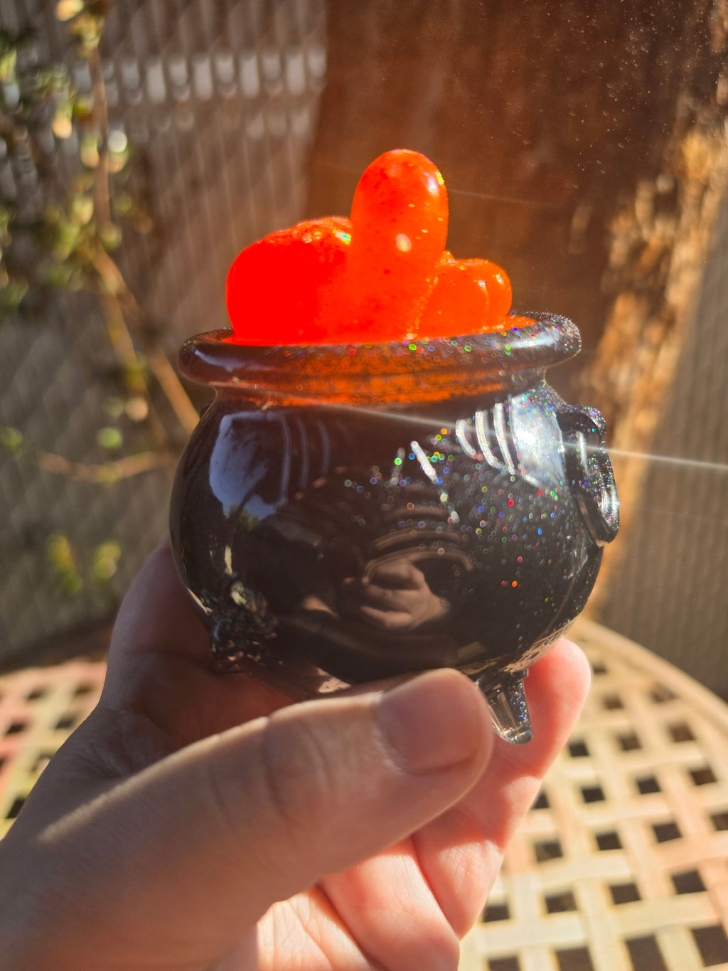 Side view of orange pumpkin resin lid with ghost on black glitter cauldron jar