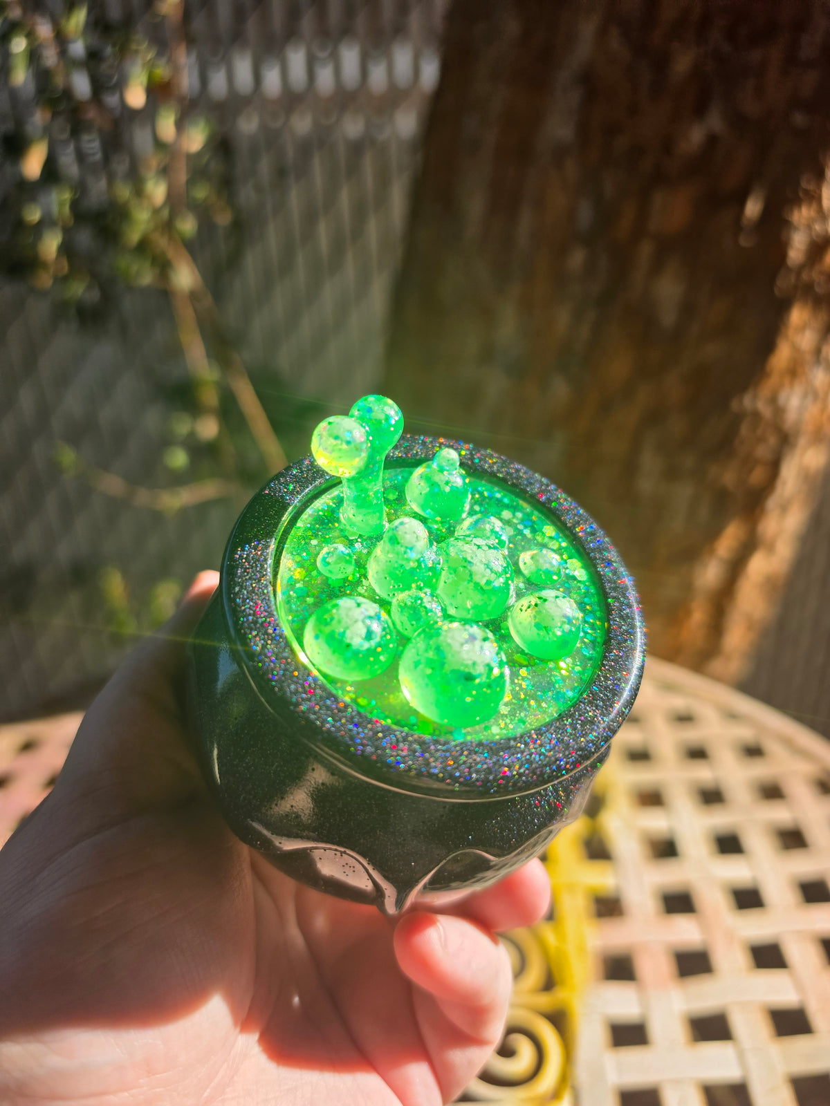 Top-down view of cauldron showing neon green sculpted bubble lid with glitter detail