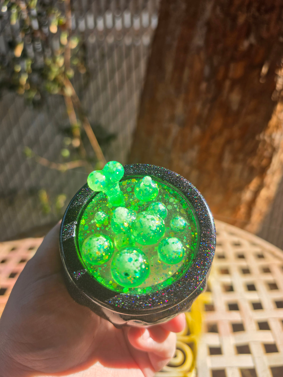Overhead view of toxic green bubbling resin cauldron lid with multicolor glitter