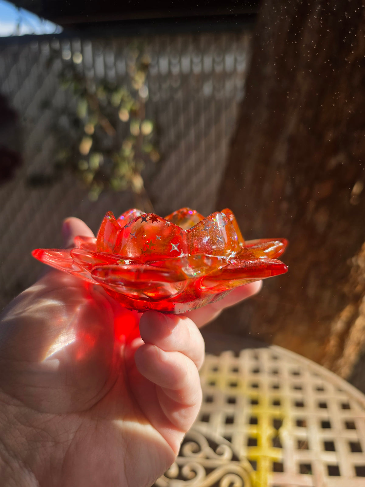 Side angle of crimson lotus resin dice throne showing two tiers of petals glowing in sunlight