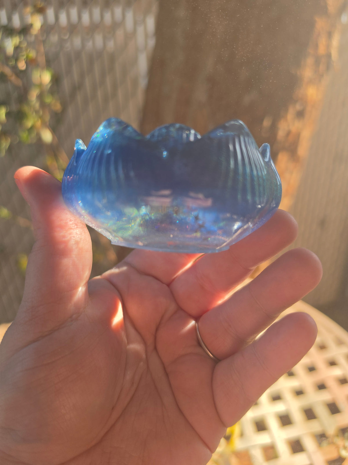 Side profile of blue lotus resin dice throne showing translucent petals glowing in natural light