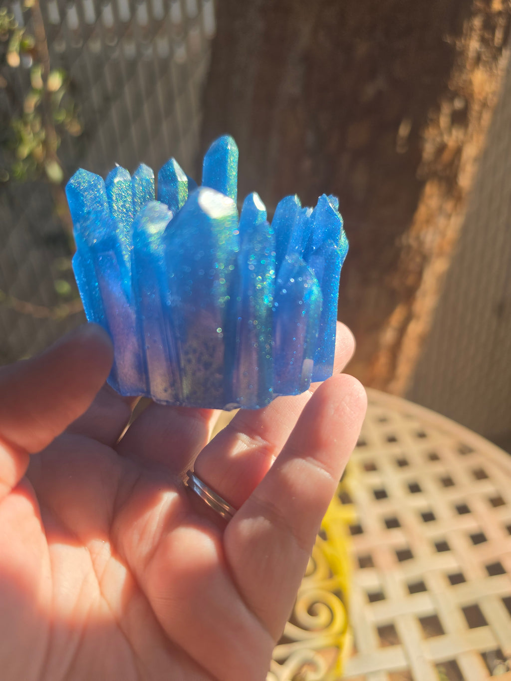 Electric blue resin crystal cluster dice throne held in hand showing iridescent green shimmer on spires