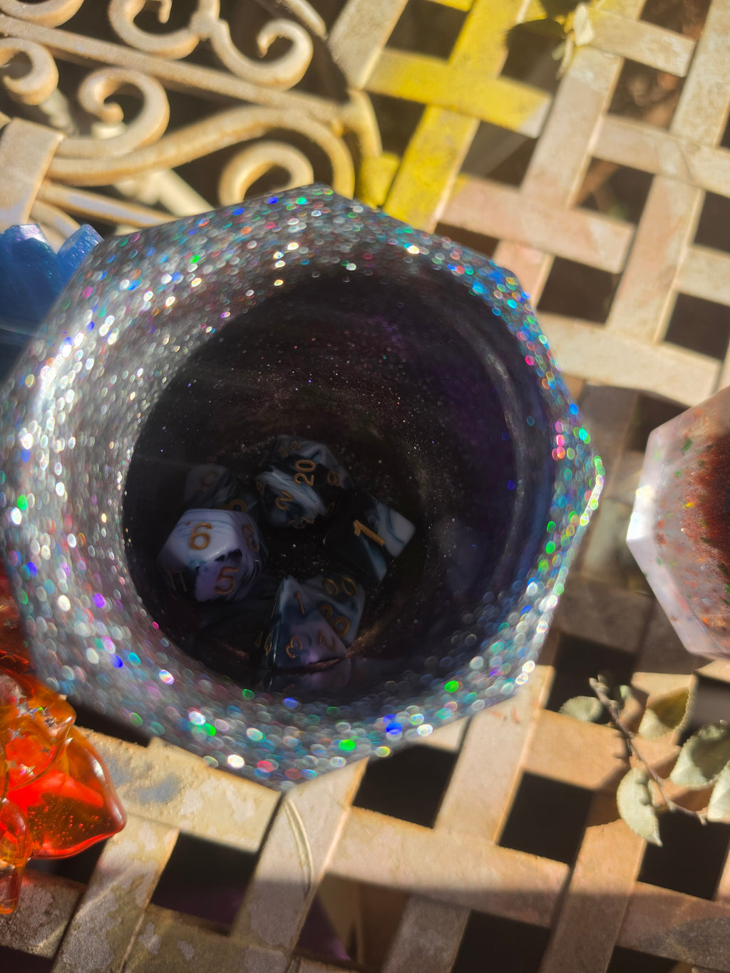 Overhead view of holographic glitter resin dice cup with dice set visible inside deep midnight purple interior