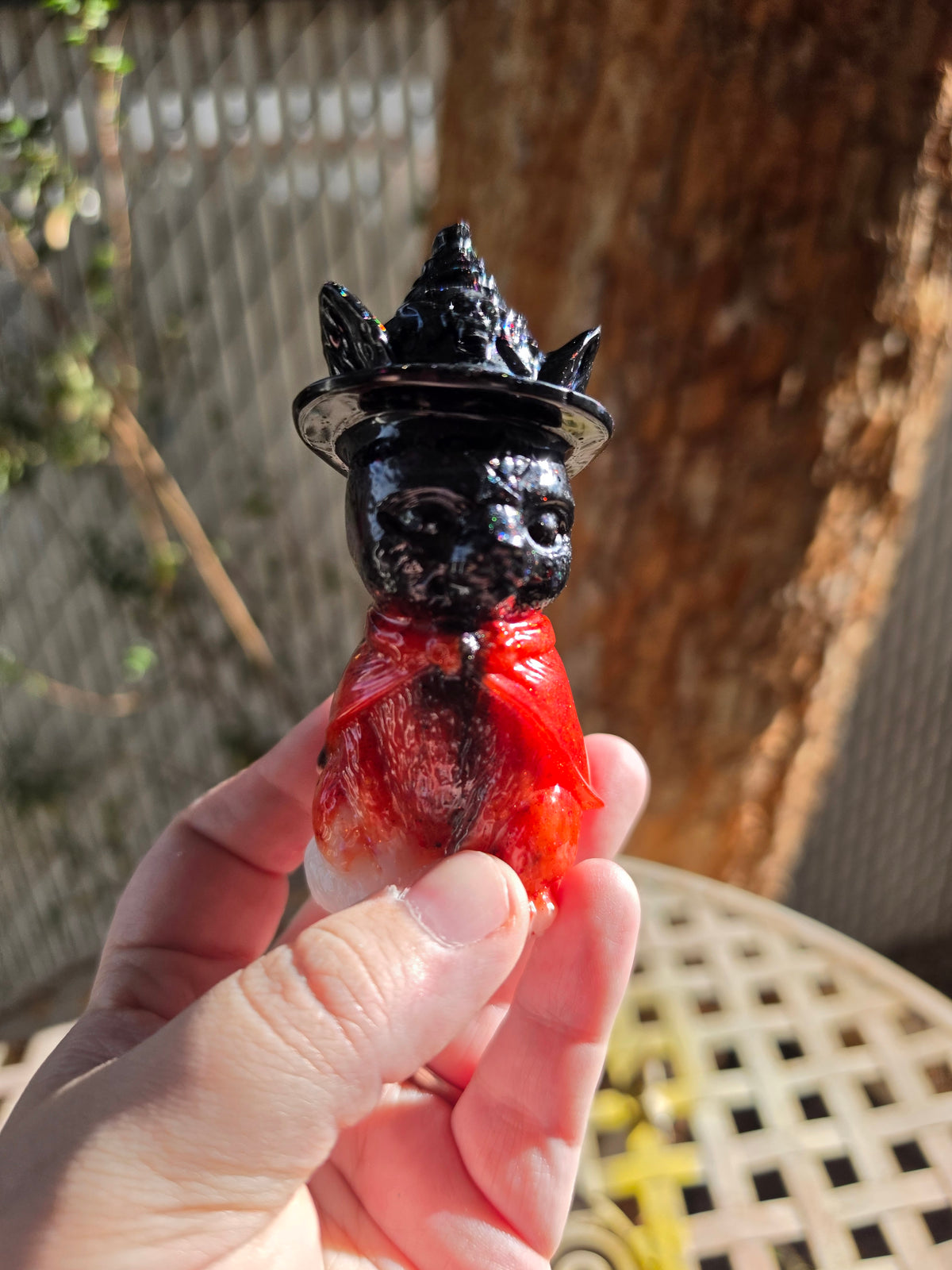 Side view of goth kitty witch statue held in a hand