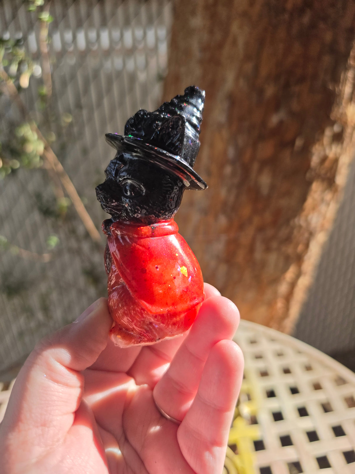 Back view of black witch hat and red-orange kitty statue