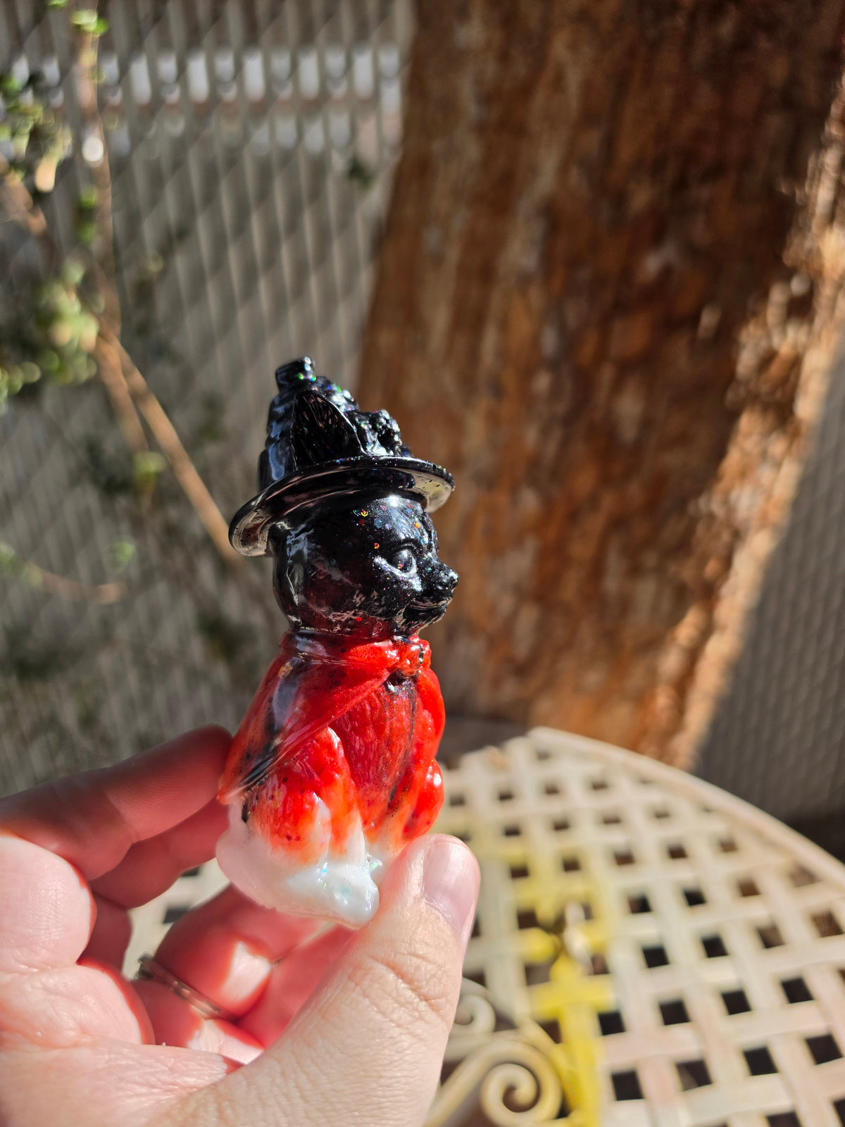 Front view of black kitty statue in a witch hat with a red-orange body
