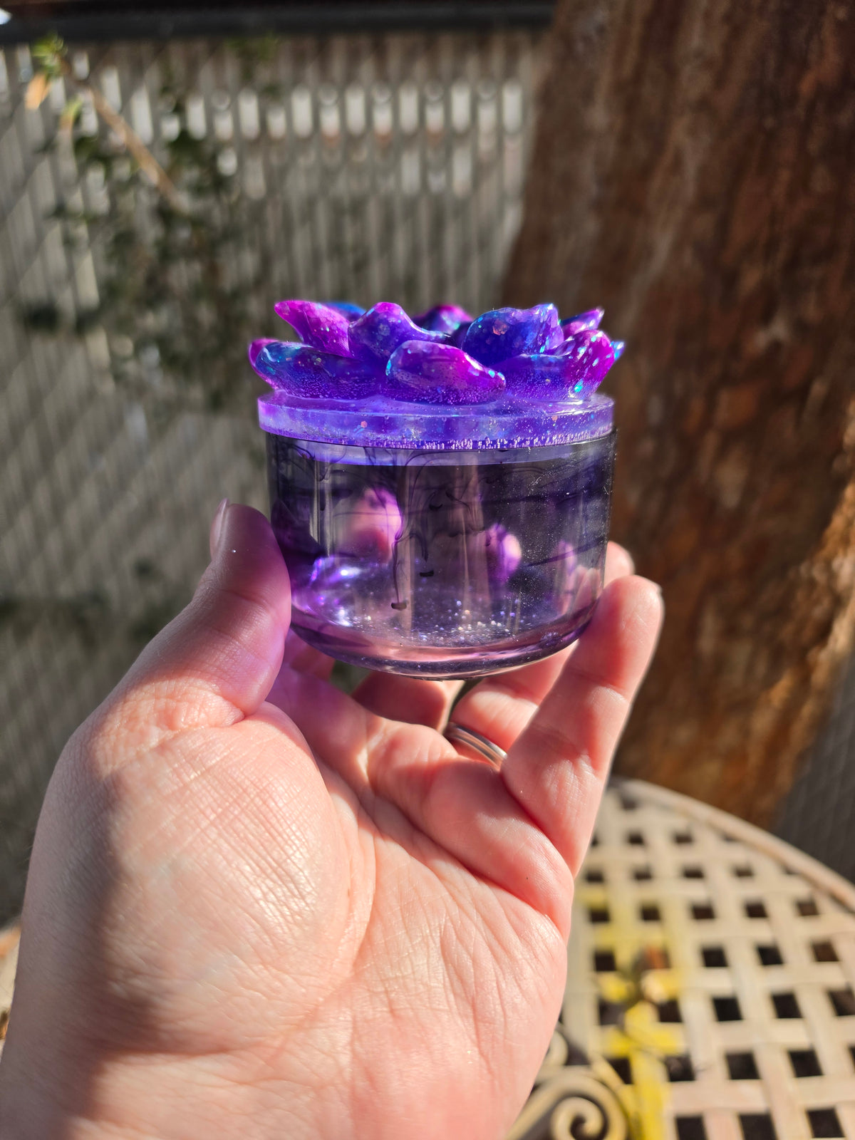 Handmade purple and blue Midnight Galaxy Bloom resin jar held in sunlight