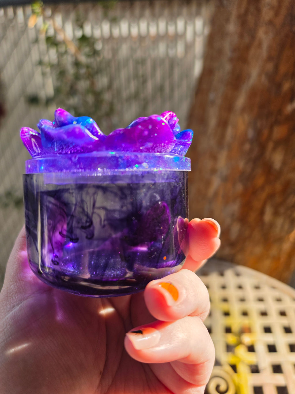 Side view of translucent purple resin trinket jar with flower lid